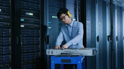 In Data Center: IT Engineer Wearing Protective Muffs Installs New Hardware Stock Footage 101184185