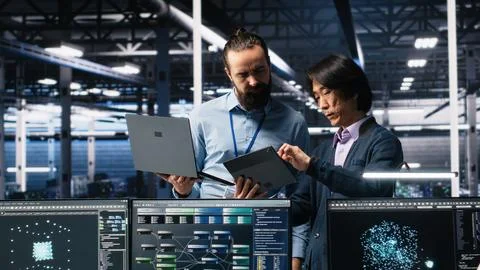 Data center manager supervising developer using device to monitor neural network Stock Photos