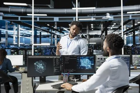 Data center manager supervising work done by engineer using deep learning tech Stock Photos