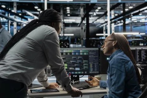 Data center manager supervising work done by engineer 写真素材