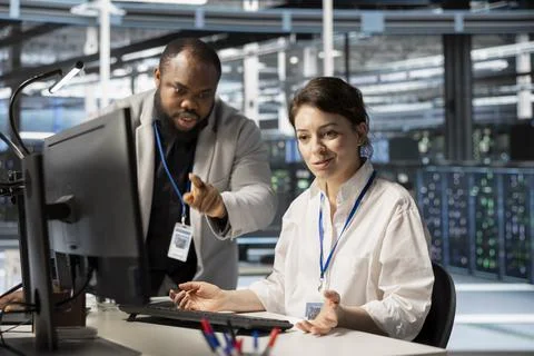 Data center manager supervising work done by engineer updating servers tech Stock Photos