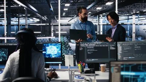 Data center manager supervising work done by programmers on neural network 写真素材