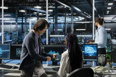 Data center manager teaching intern how to run AI forecasting simulations Stock Photos