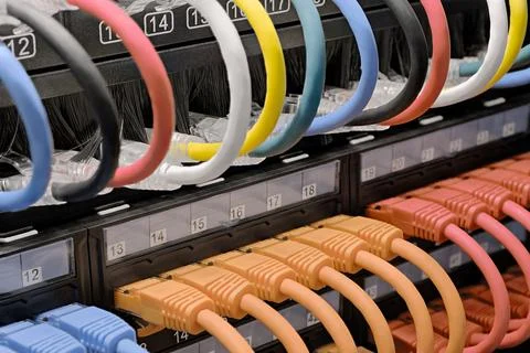 Data center, network panel, switch and connected multi-colored cables Stock Photos