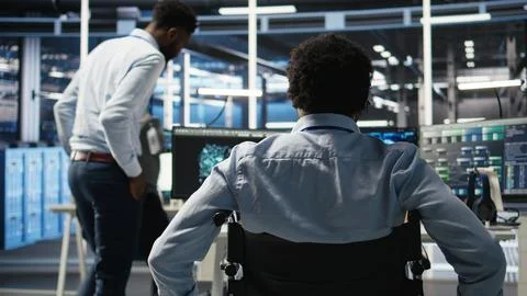 Data center programmer in wheelchair entering office uses AI node tree program 库存照片