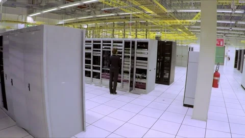Data center with server racks and employee working inside modern facility in Stock Footage 344335760