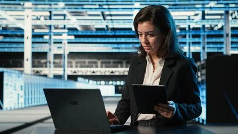 Data center specialist crosschecking settings between laptop and tablet Foto stock