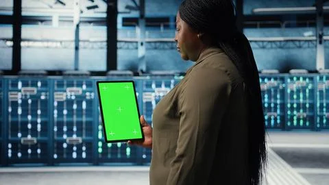 Data center specialist monitors data center metrics on green screen tablet Foto stock