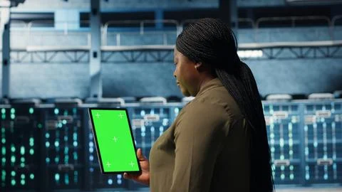 Data center specialist monitors data center metrics on green screen tablet 스톡 사진