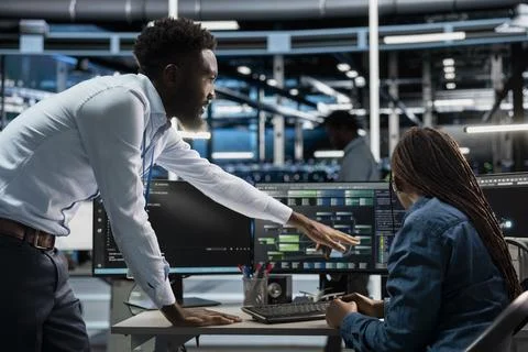 Data center supervisor offering feedback to engineer programming AI 写真素材