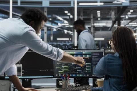 Data center supervisor overseeing admin using PC to visualize AI node trees Stock Photos