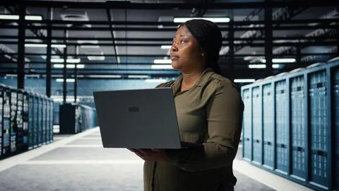 Data center system administrator using laptop to ensure error free rigs Stock Photos