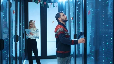 Data center team coworking inside server cabinet during Christmas time. Male and Video stock 120798511
