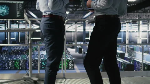 Data center team leader and worker reviewing performance dashboards of AI Stock Footage 310279168
