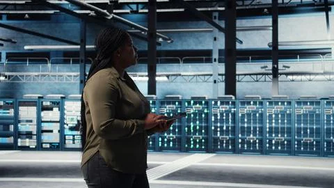 Data center technician monitors data center metrics on tablet Stock Photos