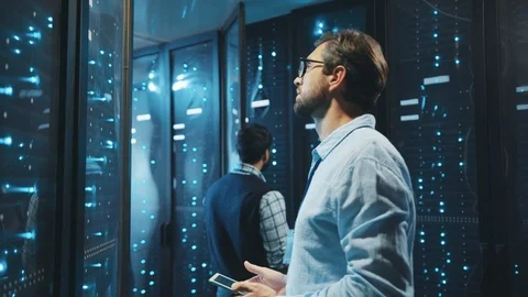 In data center two caucasian server engineers inspecting network data cabinets Stock Footage 119279103