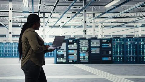 Data center worker using laptop to manage software updates for system stability Foto stock