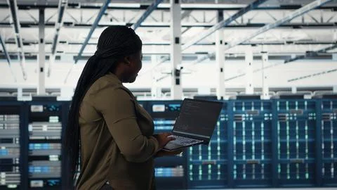 Data center worker using laptop to manage software updates for system stability Stock Photos