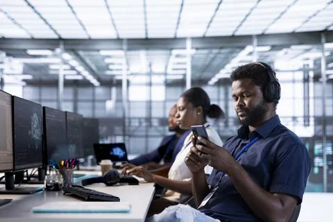 Data center worker using mobile phone, taking break from implementing AI Stock Photos