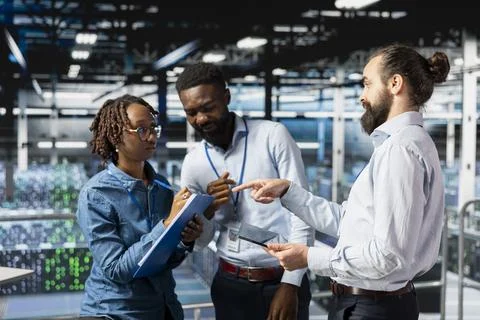 Data center workers cooperating on maintenance for server rigs Stock Photos