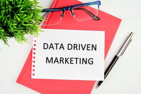 DATA DRIVEN MARKETING text written on a torn piece of paper lying on a notebo Stock Photos