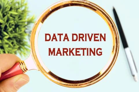 DATA DRIVEN MARKETING text written through a magnifying glass on a light back Stock Photos