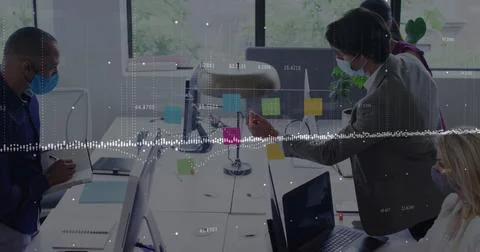 Data processing against diverse office colleagues wearing face masks discussing Stock Photos