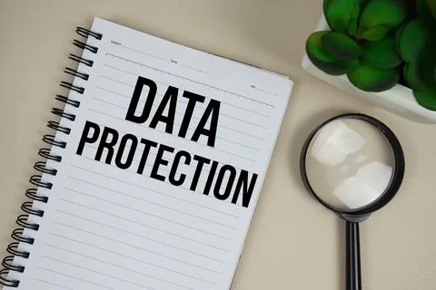 Data Protection text on paper notebook with magnifying glass on beige leath.. Stock Photos