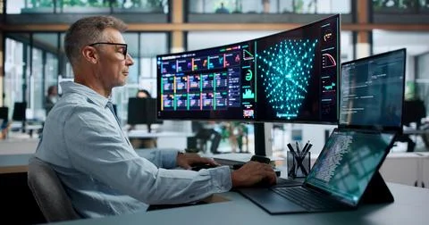 Data Scientist In Lab Coat Analyzing Neural Network Models On Dual Laptops. Foto stock
