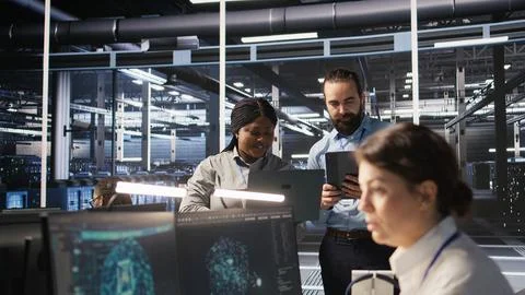 Data scientists working together in server room, reviewing neural network code Stock Photos