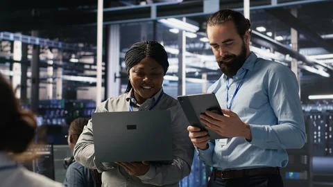 Data scientists working together in server room, reviewing neural network code Stock Photos