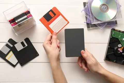 Data storage evolution: hands comparing old floppy disk with modern external  库存照片