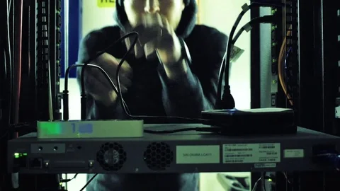 Data thief hacker in black hoodie sneaking in data center stealing hard drives Stock Footage 82799440