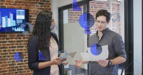 Data updating, colleagues holding tablet and papers while charts overlaying Stock Photos