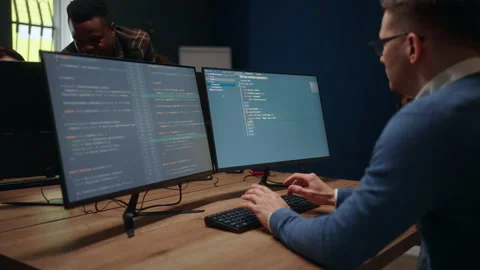 Database architect is writing computer code, view through shoulder on display Stock Footage 233726699