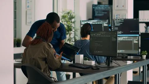 Database developer explaining algorithm to colleague coder pointing at running Stockfoto's