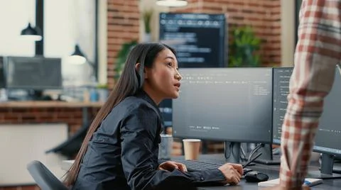 Database developer pointing pencil at computer screen with software compiling Stock Photos