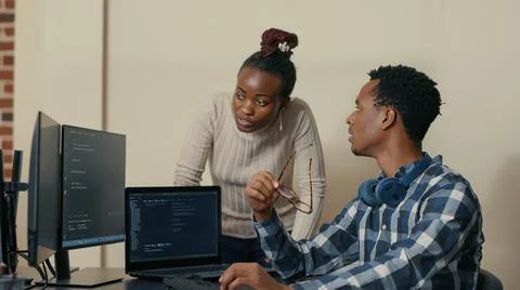 Database developer removing glasses while explaining algorithm to colleague Stock Photos
