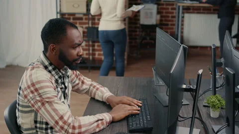 Database programer writing code and smiling while coworker walks by holding Stock Footage 168251540