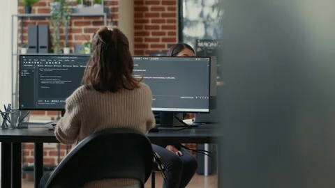 Database programer writing code in front of multiple computer screens displaying Stock Footage 168248915