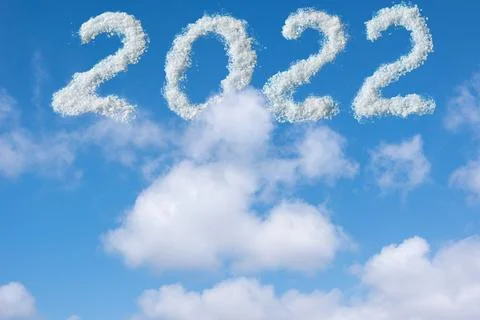 The date is 2022 written in white clouds in the blue sky. Christmas sky backg Stock Photos