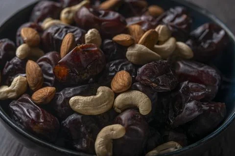 Dates and nuts in a bowl on a dark background Stock Photos