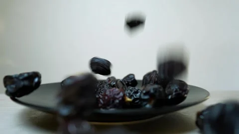 Dates falling onto a black plate against a neutral background Stock Footage 318125111