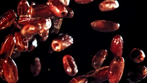 Dates falling in slow motion symbolizing time passing, set on black background Video stock 271326600