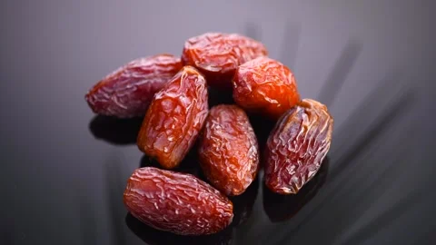 Dates fruit. Date fruits with palm tree leaf reflection on black background Stock Footage 300893655
