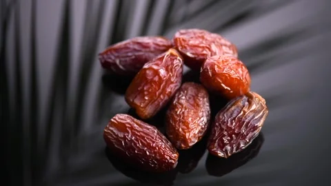 Dates fruit. Date fruits with palm tree leaf reflection rotating on black Stock Footage 313943669