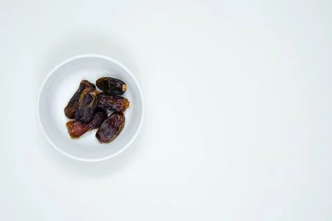 Dates or kurma in white ceramic bowl on white background. Copy space Stock Photos