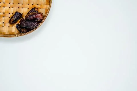 Dates or kurma in white ceramic bowl on handmade rattan plate. On white backg Foto stock
