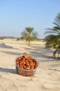 Dates in Plastic Container on Desert Sand Foto stock