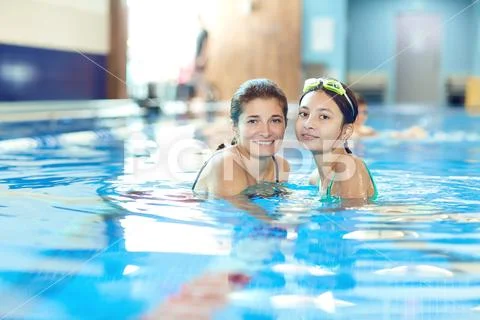 The daughter and mother swim in the swimming pool Stock Photos